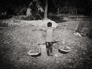 A poor child is carrying soil on baskets in rural Bangladesh.