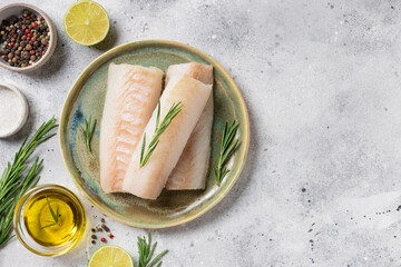 seafood background with ingredients for cooking. Raw cod loin fillet steak with aromatic herbs, spices, lime and olive oil on kitchen table. space for text - obrazy, fototapety, plakaty