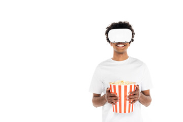 cheerful african american man with big bucket of popcorn gaming in vr headset isolated on white.