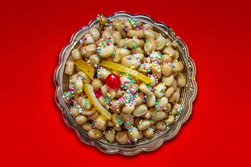 Struffoli, typical Neapolitan pastry consisting of many small balls of dough fried in oil and wrapped in warm honey. Decorated with colored sprinkles.