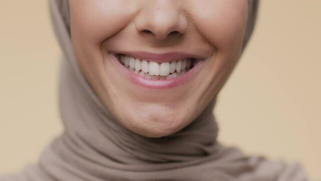 Dental hygiene concept. Close up shot of unrecognizable arab woman smiling to camera, demonstrating perfect white teeth