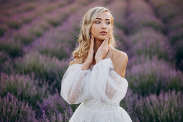 Fototapeta na wymiar Beautiful woman in wedding dress in lavender field