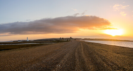Fototapeta na wymiar The long pebble spit at sunrise leading to Hurst Castle English heritage military fort and Hurst Point Lighthouse in the distance. No people. Milford on Sea, Lymington, England