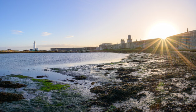 Hurst Castle English heritage military fort and Hurst Point Lighthouse just after sunrise with low tide and blue sky. Milford on Sea, Lymington, Hampshire, England