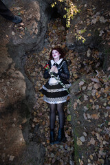 The dead girl lies in an earthen hole in fallen leaves with a red carnation in her hands. Halloween witch games.