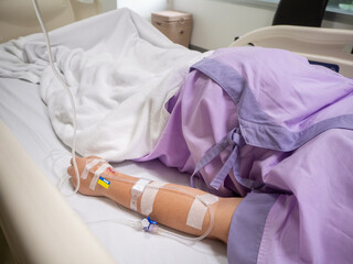 saline solution on hand of women patient in pink clothes lying on the hospital bed