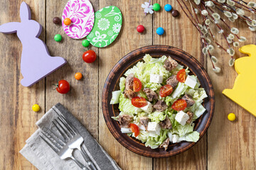 Holiday food, easter salad. Salad with chinese cabbage, feta, cherry tomatoes and canned tuna and vinegar dressing on a festive table. Top view flat lay.