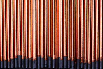 A background of round graphite gouging electrodes stacked vertically together. New copper straight...