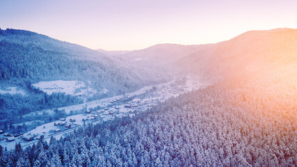 Stunning sunrise over snowy mountains in the alps, norway, finland, ukraine, the sun's rays penetrate through the trees. Mountains and snow, skiers go to the mountains.