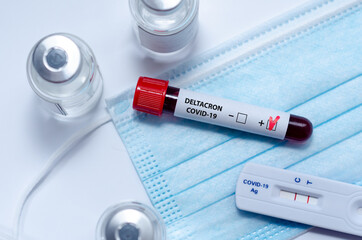Test tube with positive  Deltacron COVID-19 test blood sample and positive covid-19 rapid test in...