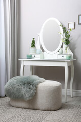 White dressing table with decor near beige wall in room