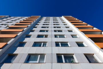 Tall block of flats from the 20th century with 11 floors and orange balcony parapets from frog...