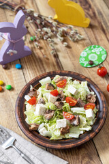 Holiday food, easter salad. Salad with chinese cabbage, feta, cherry tomatoes and canned tuna and vinegar dressing on a festive table.
