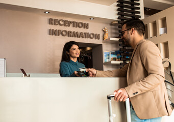 Guest pays for the stay at the hotel to female receptionist with a credit card at the reception.