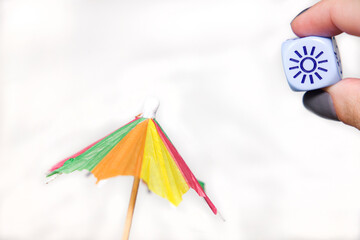 representation of summer with a paper umbrella and a dice with a sun