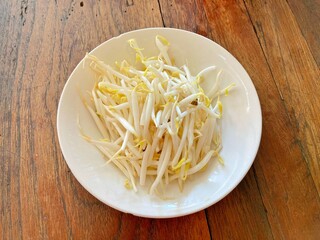 Bean sprouts in white bowl on wooden background.