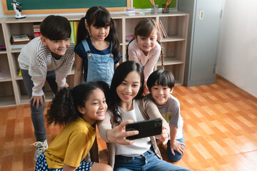 Diverse school kids and Asian woman Teacher taking selfie with mobile phone or smartphone.
