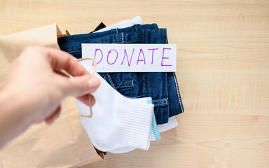 A man's hand holds a donation bag. Selective focus on lettering donation on clothing.