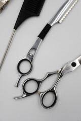a set of professional combs, scissors, razors and hairpins unfolds on a light background