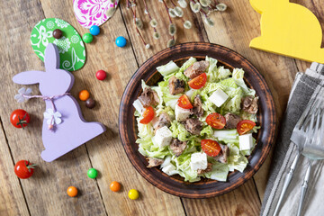 Holiday food, easter salad. Salad with chinese cabbage, feta, cherry tomatoes and canned tuna and vinegar dressing on a festive table. Top view flat lay.