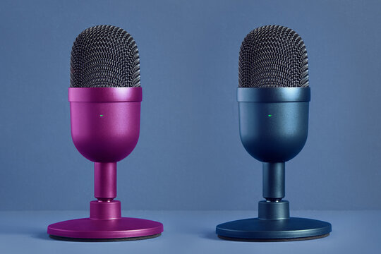 Two minimalist, modern and colorful microphones for streaming, gaming and podcasting face to face on a pastel color background with texture. Technology and entertainment. Product and design.