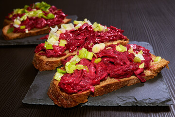 Homemade rye bread bruschetta with beetroot, herring, red and green onion salad. Traditional snack.