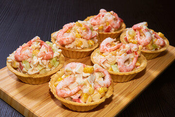 Salad of corn, shrimp, fresh cucumbers, crab sticks and sauce in tartlets. Traditional snack.