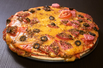Three-layer homemade pizza with cheese, sausages, ham and olives. Close-up, selective focus.