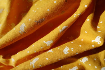 Folded amber yellow cotton fabric with birds print