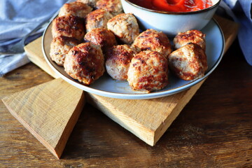 Roasted meatballs with tomato sauce , delicious meat cutlets on wooden table. Top view