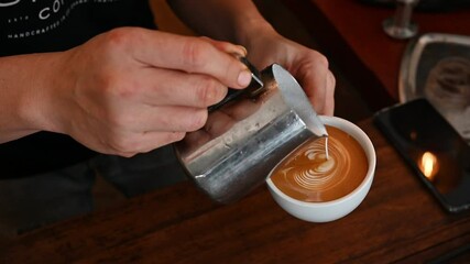 Footage video of Barista trying to pouring steamed milk to espresso coffee to making latte art. A latte is a coffee drink made with espresso and steamed milk.