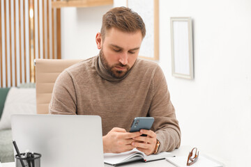 Young man using smartphone while working at home