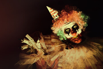 Terrifying clown in darkness. Halloween party costume