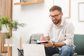 Fototapeta premium Young man working with notebook and laptop at home, space for text
