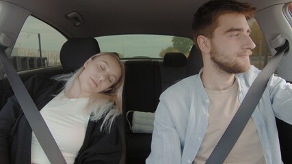 A guy and a girl are driving a car. The girl is sleeping in the car