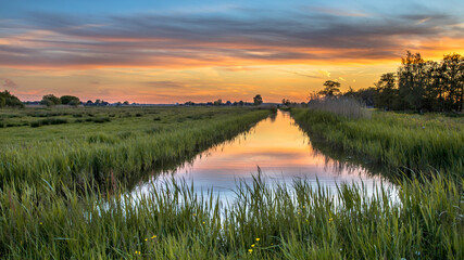 Sonnenuntergang über dem Kanal in der historischen holländischen Landschaft