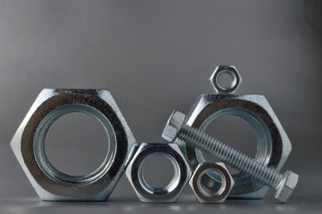 composition of new bolts and nuts of different sizes on a gray background.