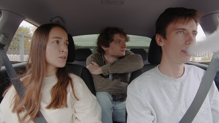 Fototapeta premium A small group of people is riding in a car. The guy smokes in the car. People are driving in a car