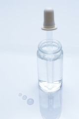 glass transparent jar and a cosmetic pipette with liquid droplets on a white background.