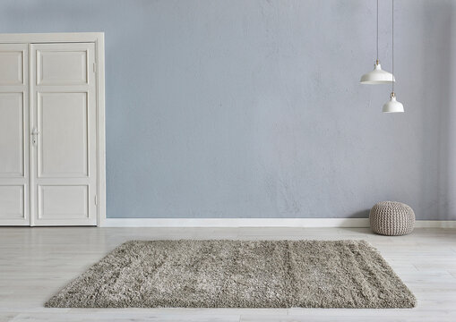 Grey stone wall background with white wooden door, lamp carpet and home style, poster decoration room interior.