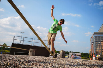 Caucasian white man on slackline wearing a green shirt and sunglasses