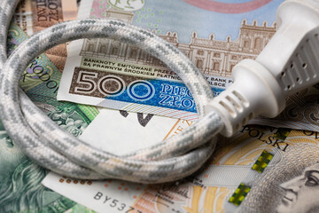 Electric cable with socket and many Polish banknotes. Rise of electricity price in Poland. Photo...