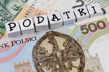 The wording "Podatki" translated as "Taxes" plus many Polish banknotes. New tax rules in Poland from 2022. Photo taken under artificial, soft light
