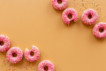 Frame of pink glazed donutes with sprinkles, top view