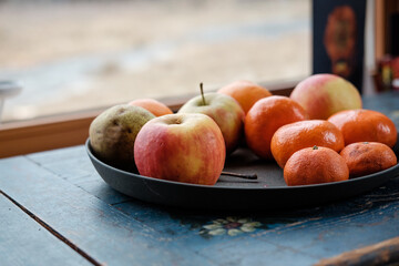Apples and tangerines in a bowl on a wooden table