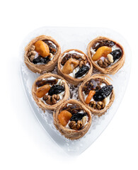 Traditional arabic and turkish sweets pastry dessert kadaif with nuts and dried sweetened fruits isolated on white