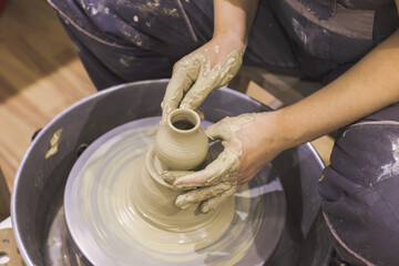 Pottery workshop. Closeup of woman artist hands molding clay on pottery wheel. Creative handmade craft. Ceramic studio.