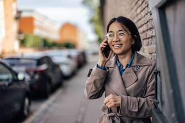 Smiling Asian woman talking on smartphone.