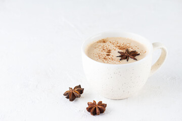 Homemade masala tea with milk, ginger root and spices in a mug on the table. Lactose free, vegan.