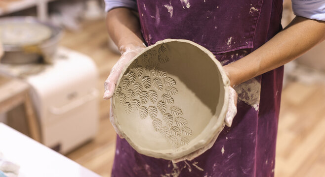 Female pottery artist working on clay bowl. Creative handmade craft. Ceramic studio.